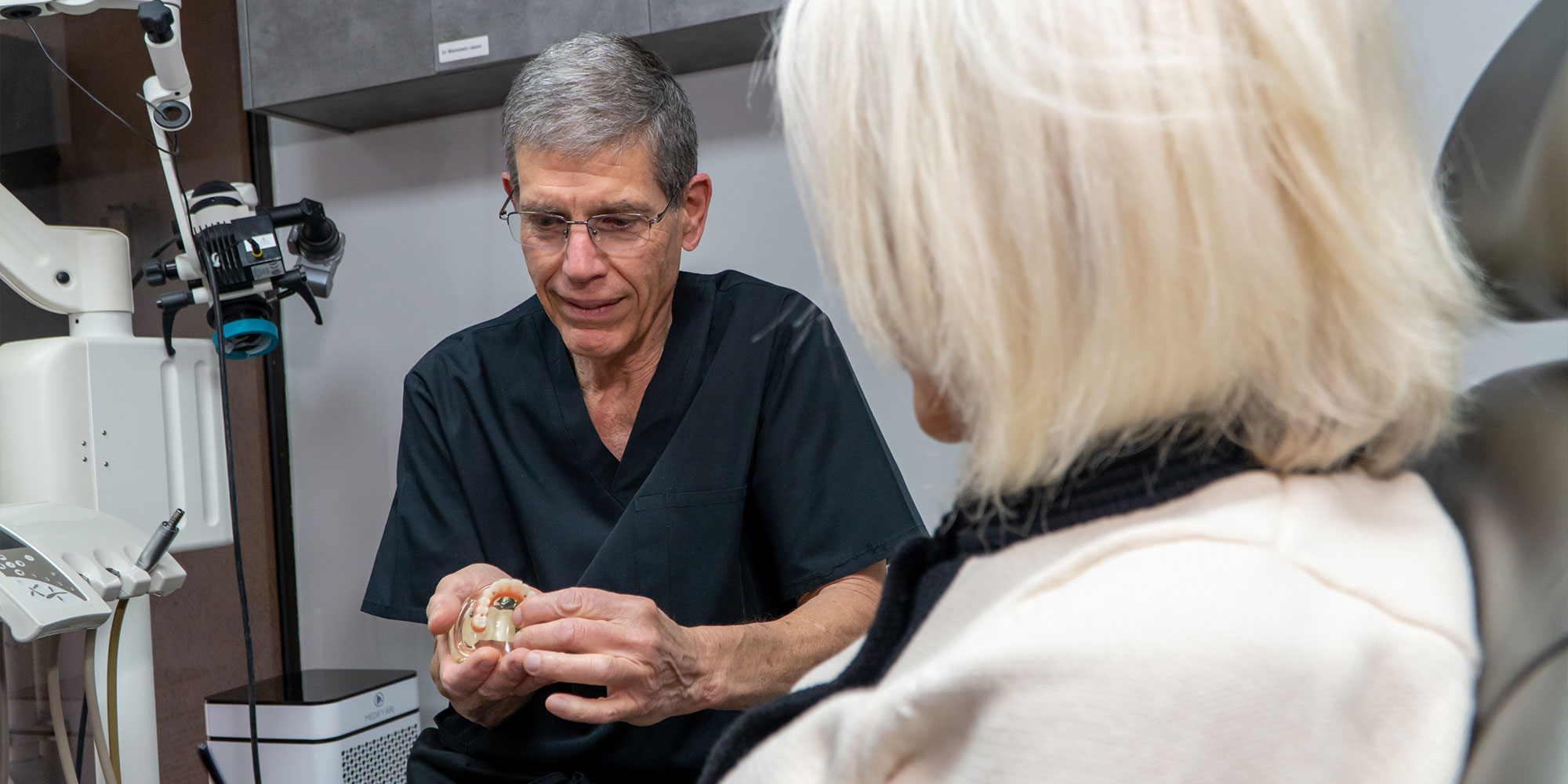 doctor looking over dental arch model with patient
