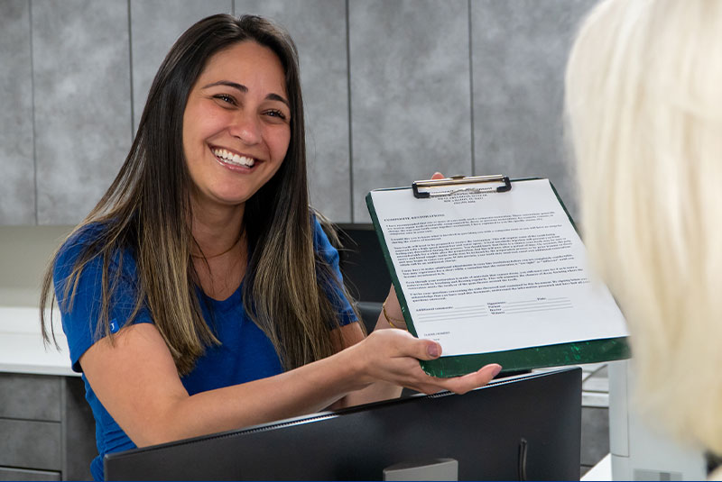 staff member showing patient clipboard for checking in at the dental center