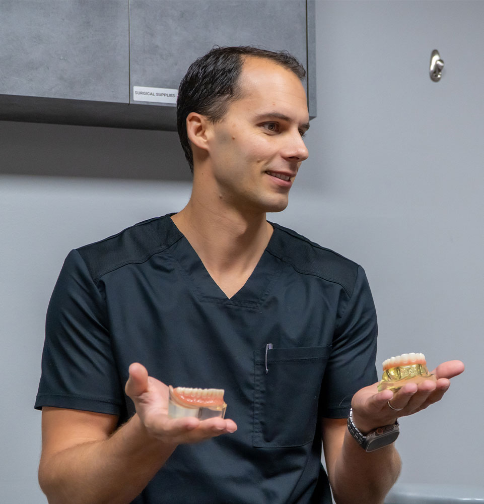 doctor holding two different dental arch models to show patient