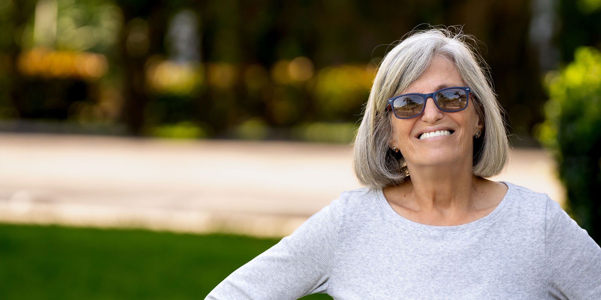 headshot of patient smiling brightly outside of the dental center